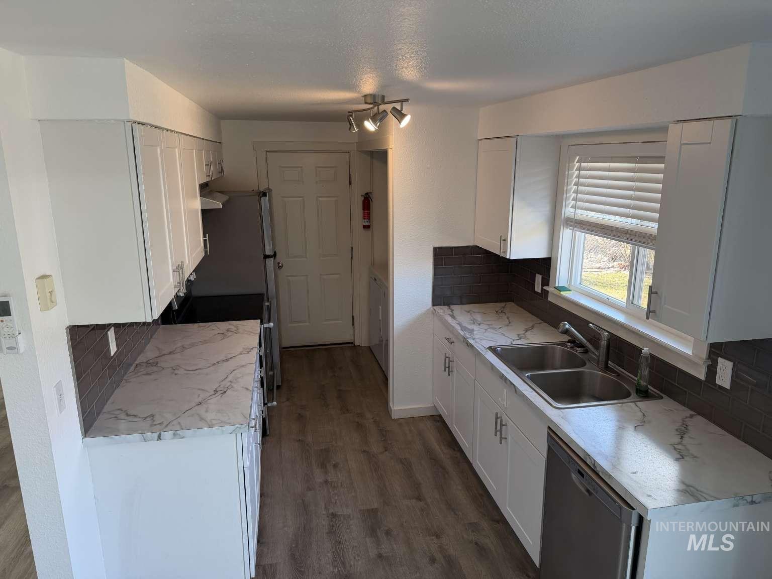 211 Jasper Avenue Middleton, ID 83644 - Photo 7 of 25 Kitchen with backsplash, white cabinets, light countertops, stainless steel appliances, and a textured ceiling