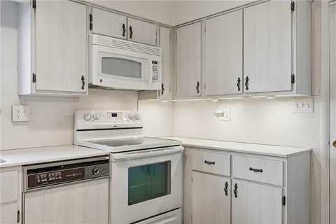 a kitchen with white cabinets and appliances