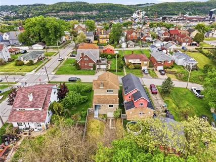 an aerial view of residential houses with outdoor space and trees