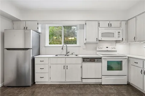a kitchen with white cabinets and white appliances