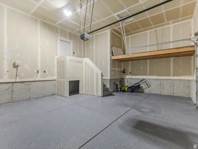 11759 South Watercourse Road South Jordan, UT 84009 - Photo 26 of 33 Spacious garage featuring a durable epoxy-coated floor, high ceilings, built-in overhead storage, an automatic garage door opener, and a utility sink rough-in