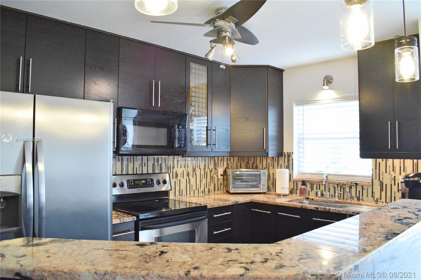 a kitchen with stainless steel appliances kitchen island granite countertop a sink refrigerator and cabinets