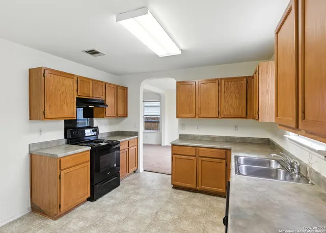 a kitchen with a stove a sink a microwave a counter top space and cabinets