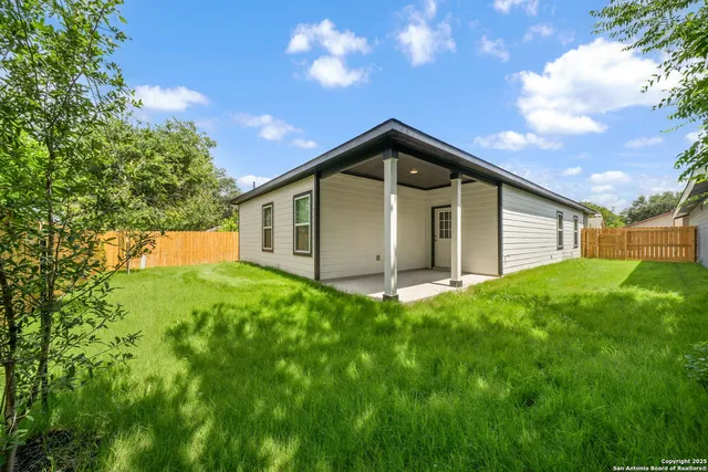 a backyard of a house with plants and large tree