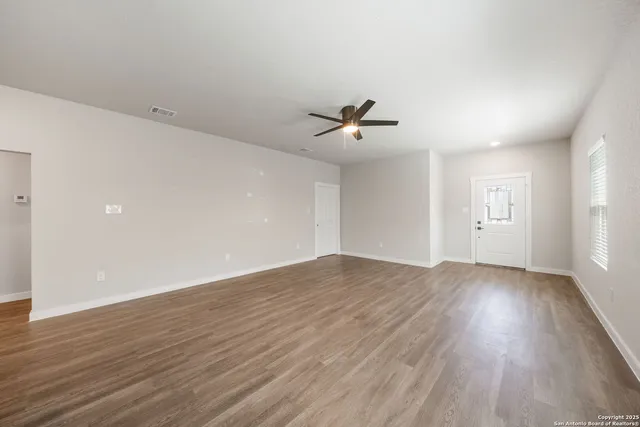 an empty room with wooden floor and windows