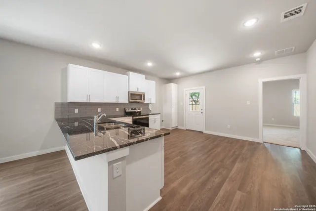 a kitchen with stainless steel appliances granite countertop a sink a stove and a microwave