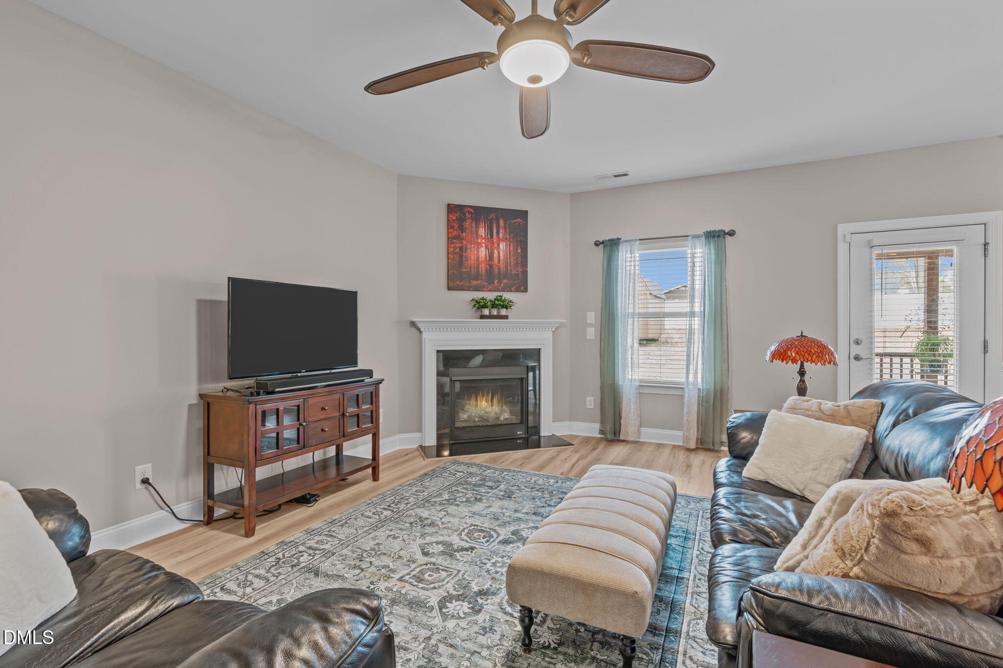 Corner fireplace creates focal point for cozy ambiance. Bright windows overlook back yard and door to screened porch.