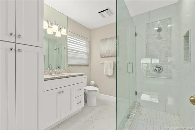 a bathroom with a granite countertop sink a toilet and shower