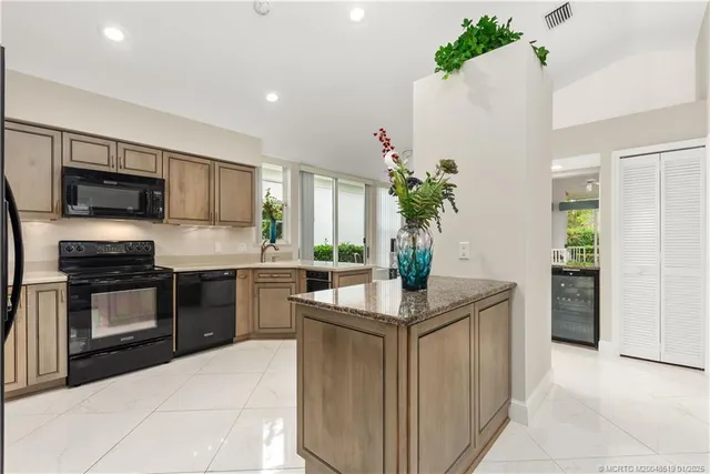 a kitchen with kitchen island granite countertop a sink stove and refrigerator