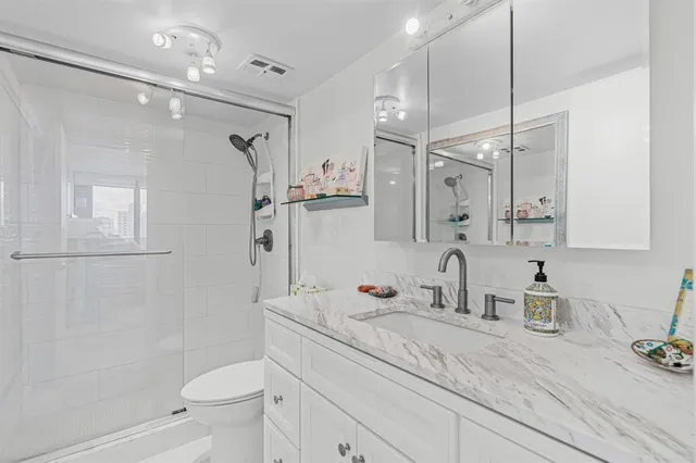 a bathroom with a granite countertop sink a toilet and shower