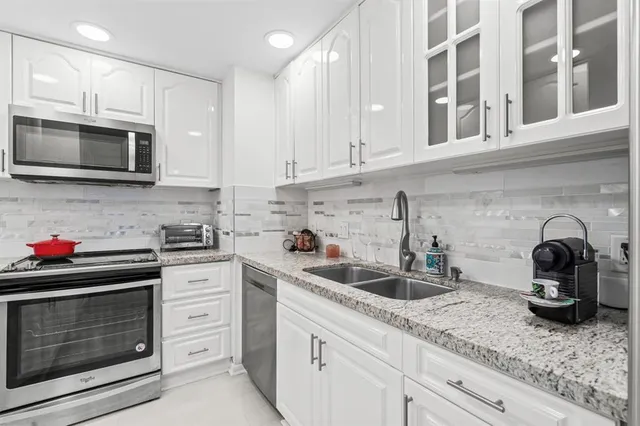 a kitchen with stainless steel appliances granite countertop white cabinets a stove a sink and dishwasher