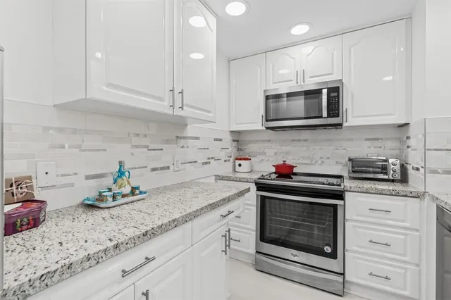 a kitchen with granite countertop white cabinets stainless steel appliances and sink