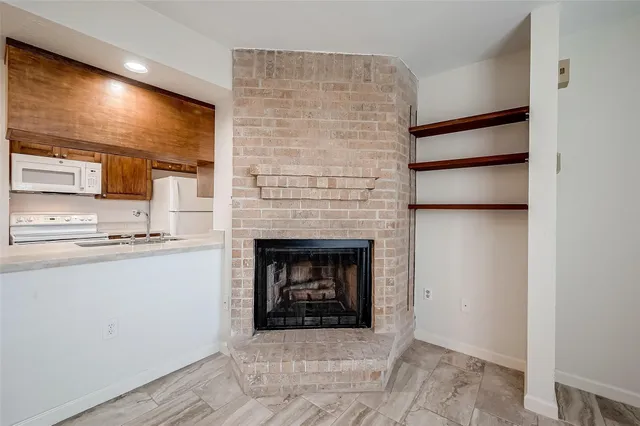 a living room with stainless steel appliances white cabinets and a fireplace