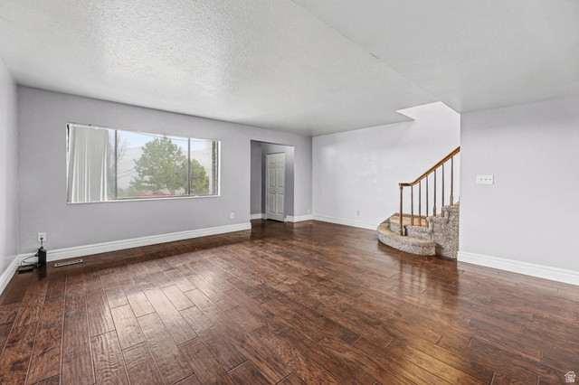 34 Benchmark Village Tooele, UT 84074 - Photo 6 of 35 Unfurnished living room with dark wood finished floors and a textured ceiling