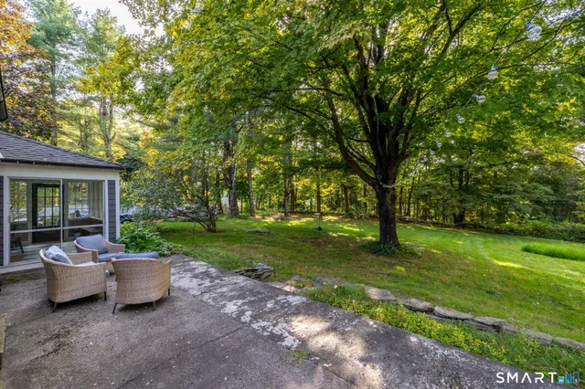 a view of a patio with table and chairs potted plants and large tree