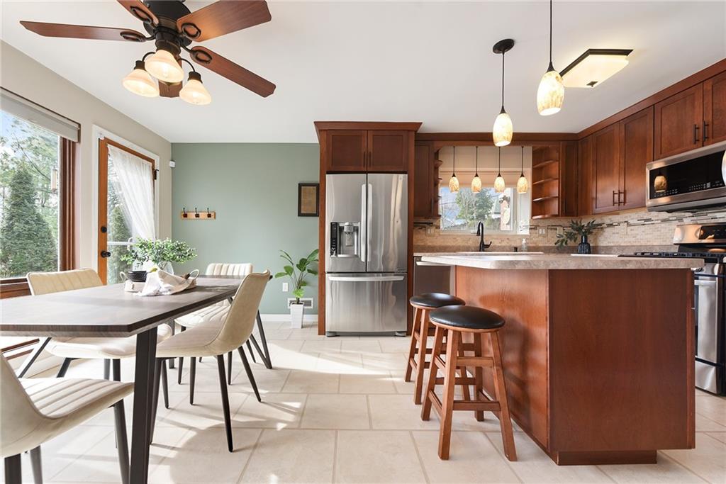 6913 Merton Road Pittsburgh, PA 15202 - Photo 14 of 48 a kitchen with stainless steel appliances granite countertop a sink a stove a refrigerator a dining table and chairs with wooden floor