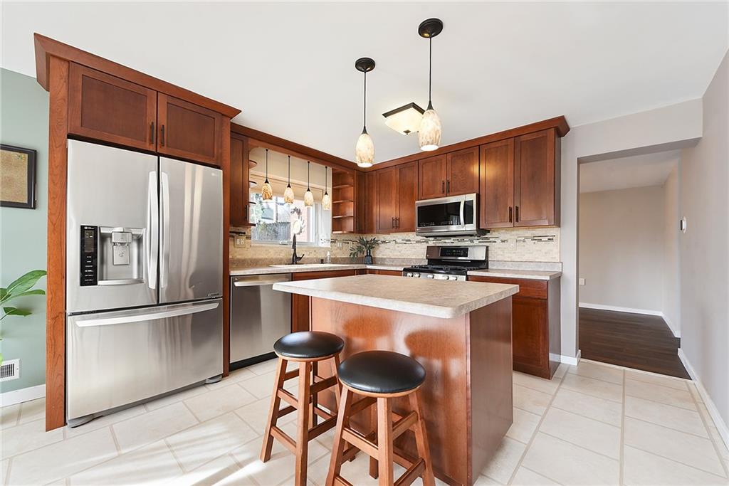 6913 Merton Road Pittsburgh, PA 15202 - Photo 21 of 48 a kitchen with stainless steel appliances granite countertop a refrigerator a stove a sink a dining table and chairs with wooden floor