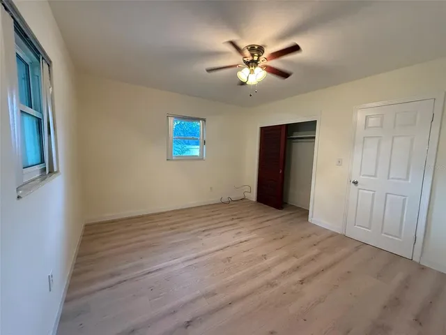 a view of an empty room with wooden floor and a chandelier fan