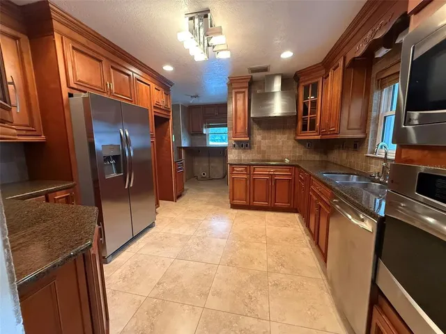 a kitchen with stainless steel appliances granite countertop a refrigerator a sink dishwasher a stove and white countertops with wooden floor