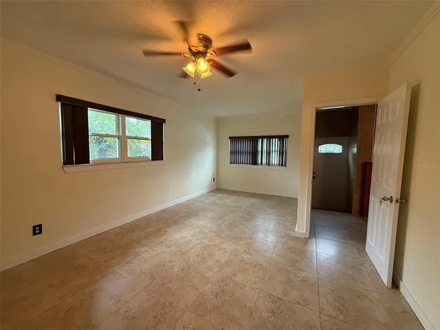 an empty room with chandelier fan and windows