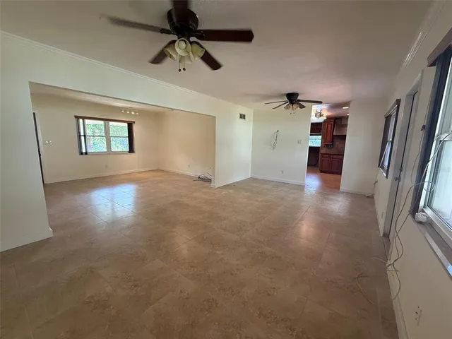 en empty room with windows and ceiling fan