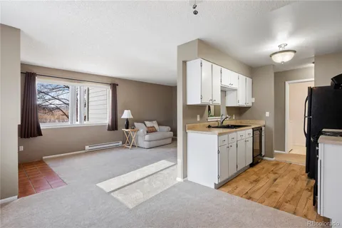 a large kitchen with a refrigerator a stove a sink a dining table and chair with wooden floor