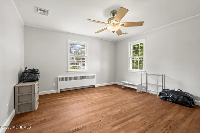 a view of an empty room with a window and wooden floor