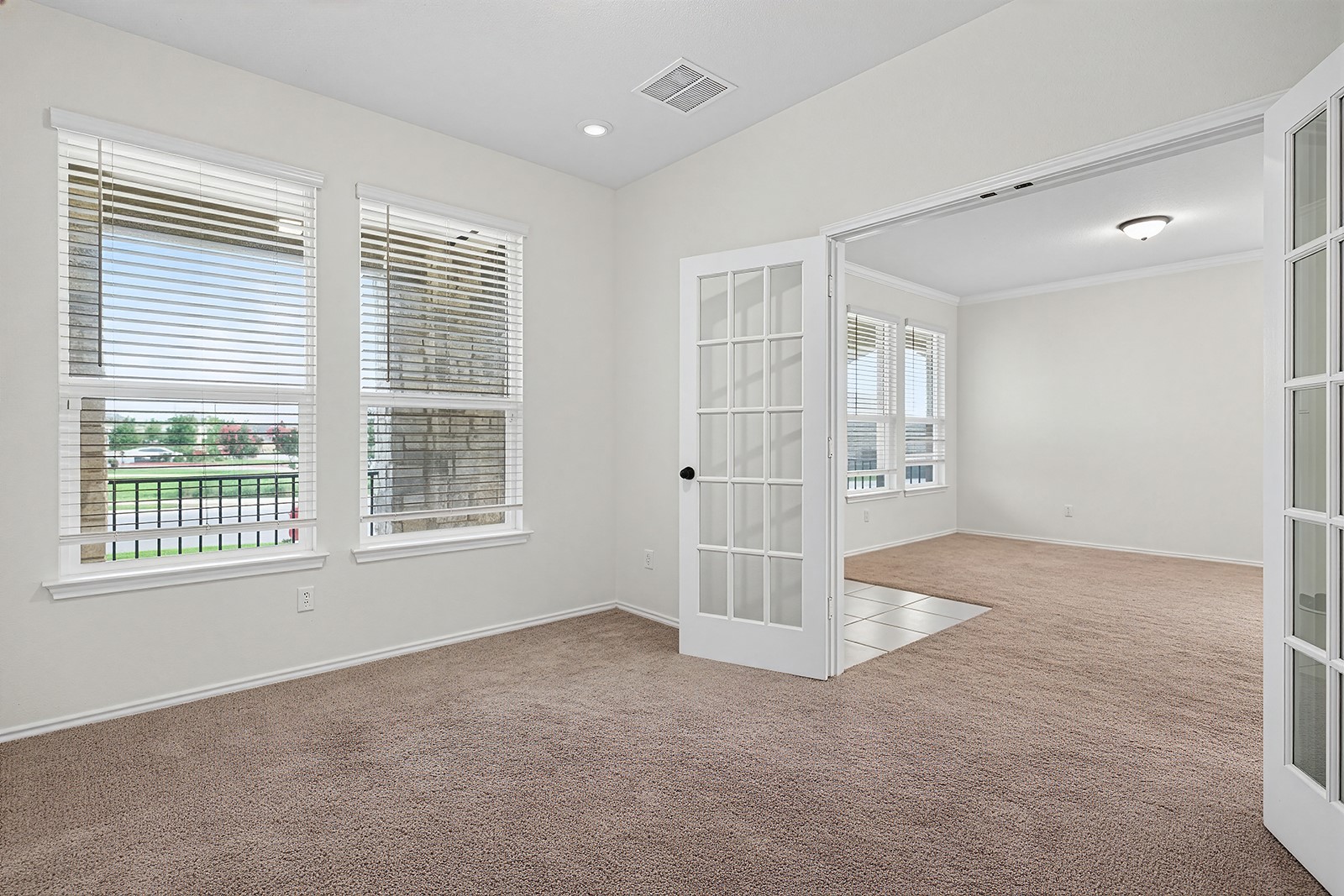 4600 Ercolano Lane Round Rock, TX 78665 - Photo 9 of 37 Carpeted room with white walls, two large windows with blinds, and French doors leading to another room