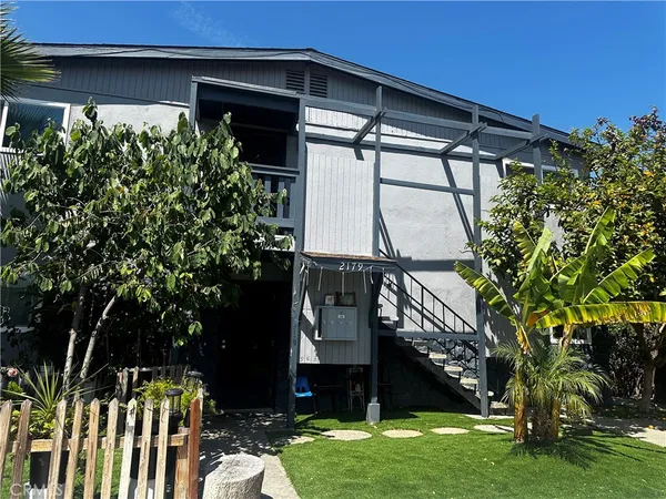 a view of a house with a small yard and a large tree