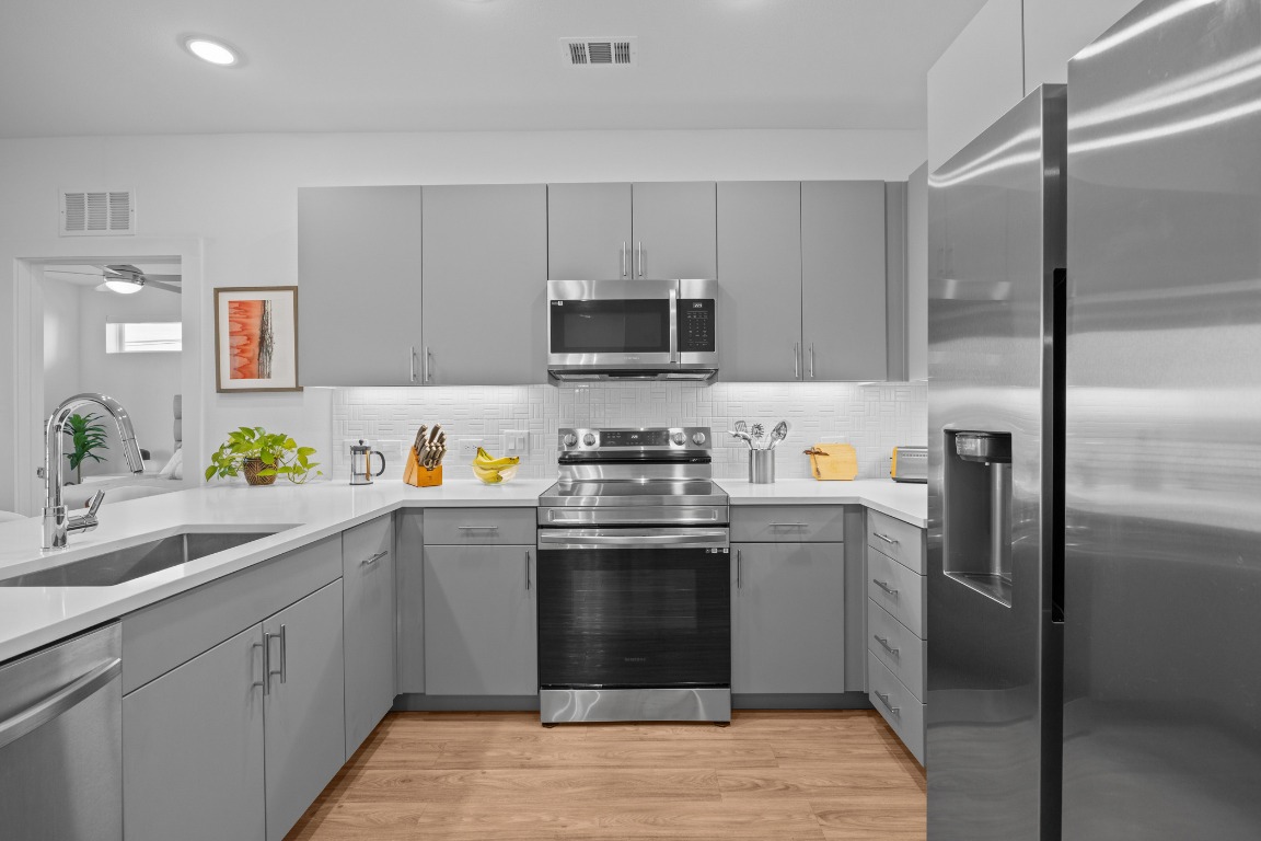 4801 Springdale Road, Unit 1401 Austin, TX 78723 - Photo 14 of 40 a kitchen with stainless steel appliances granite countertop a stove a sink and a refrigerator