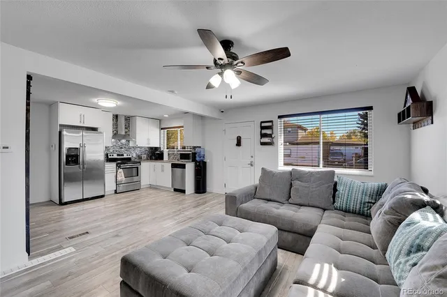 a living room with furniture kitchen area and a window