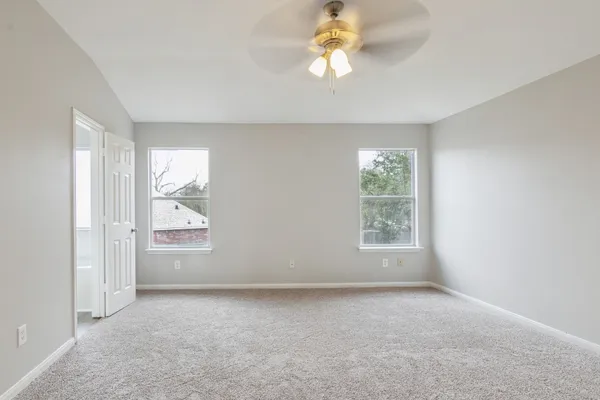 an empty room with windows and fan