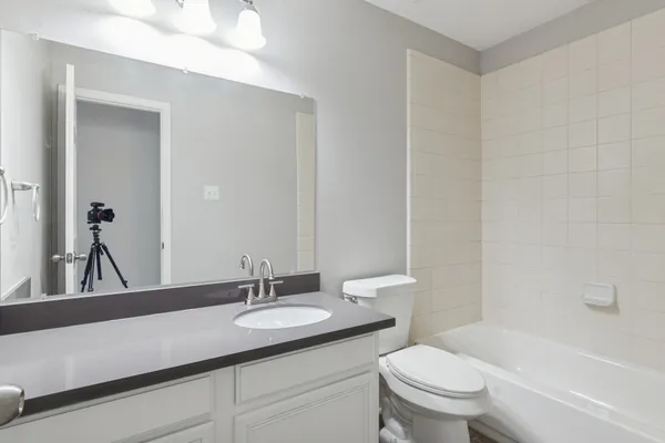 a bathroom with a granite countertop sink a toilet a mirror and bathtub