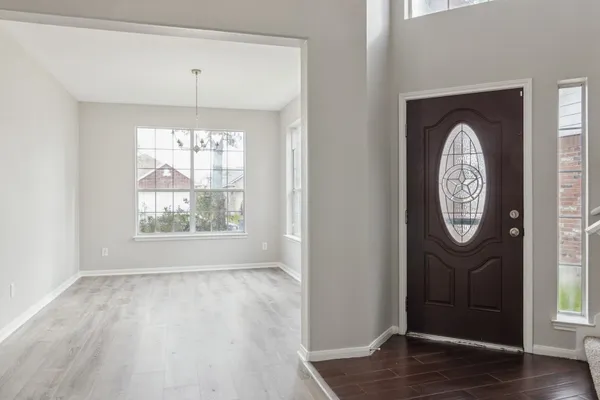 an empty room with wooden floor a fan and a window
