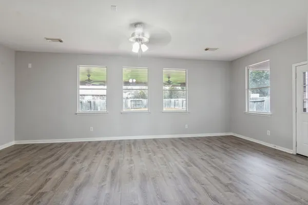 an empty room with wooden floor and windows