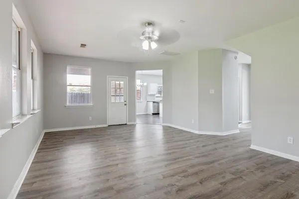 a view of an empty room with a window and wooden floor