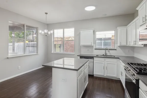 a kitchen with granite countertop a sink appliances wooden floor and a window