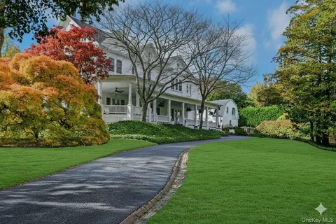 a view of a brick house next to a yard with big trees