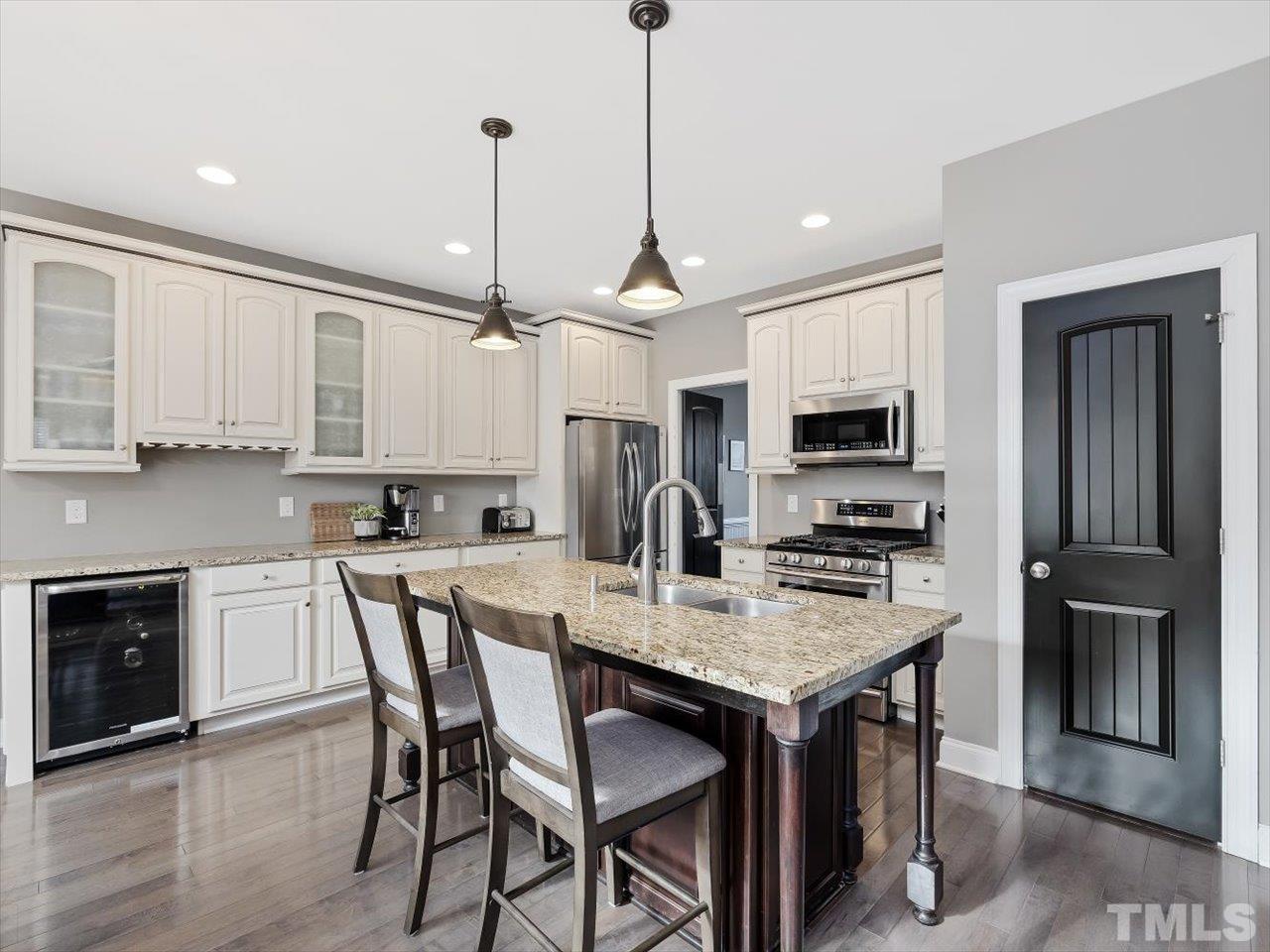 911 Wade Avenue Raleigh, NC 27605 - Photo 16 of 60 a kitchen with stainless steel appliances granite countertop a stove top oven a refrigerator a sink and a dining table with wooden floor