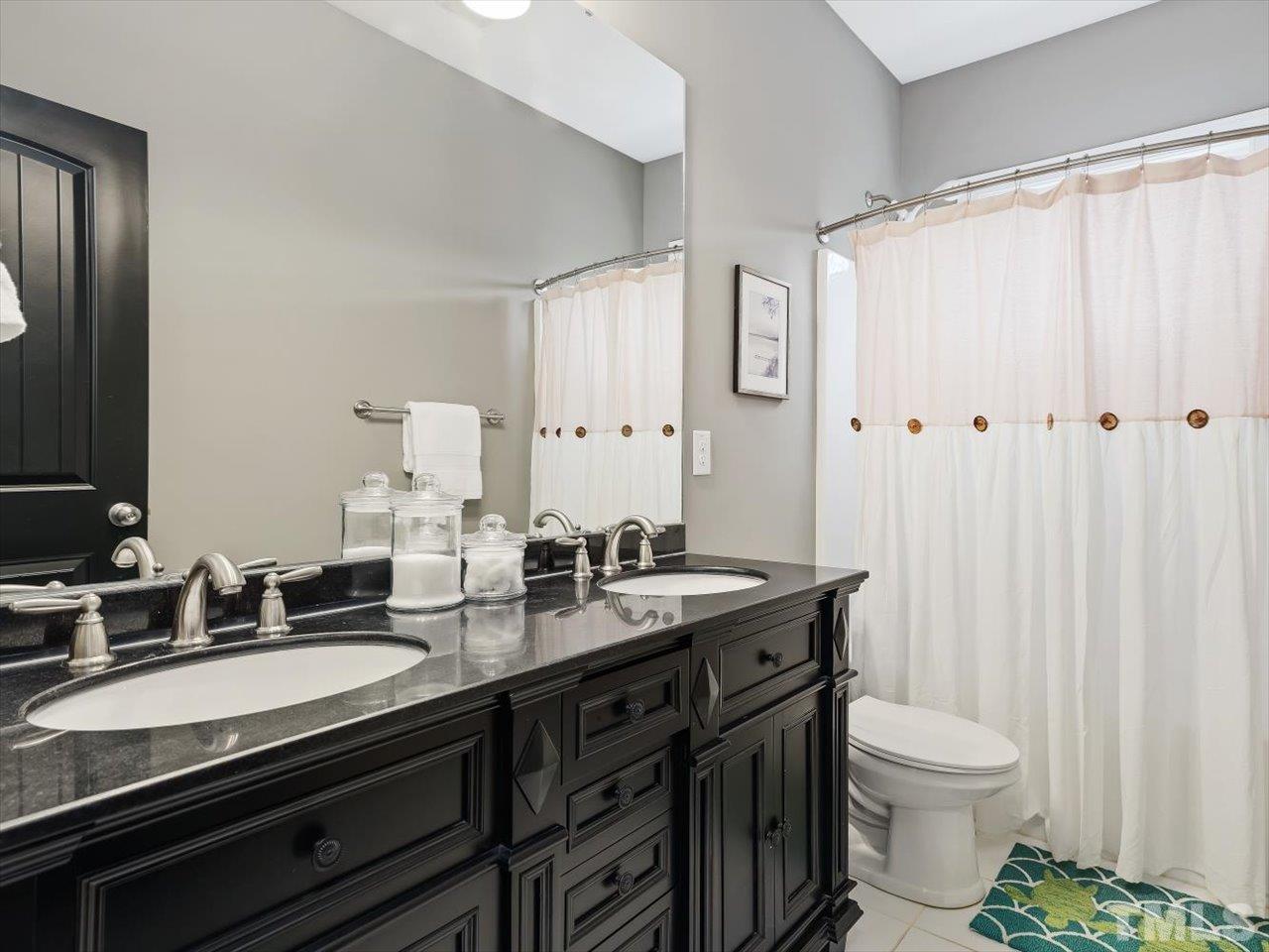 911 Wade Avenue Raleigh, NC 27605 - Photo 41 of 60 a bathroom with a double vanity sink toilet and a mirror