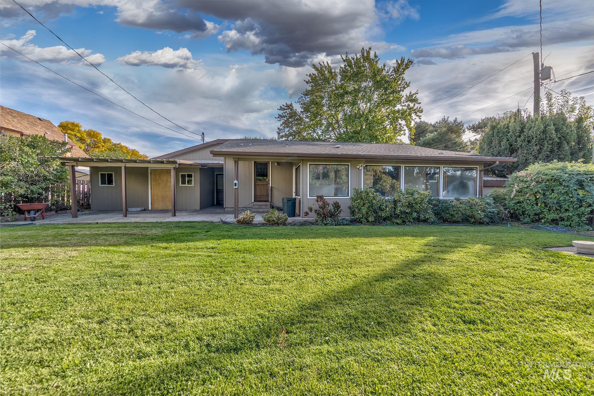 340 Pioneer Road Weiser, ID 83672 - Photo 31 of 44 Expansive green lawn, covered patio, mature landscaping, large windows, and an exterior with a neutral finish