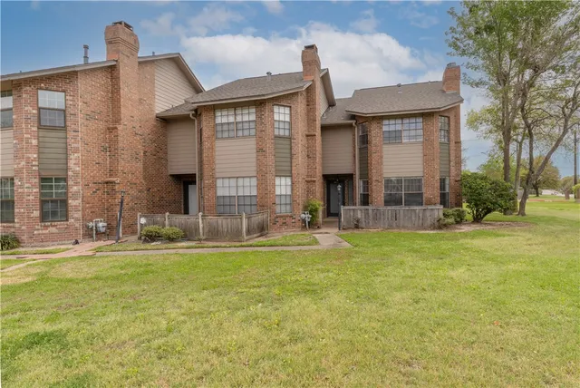 a view of a brick house with a large windows and a yard
