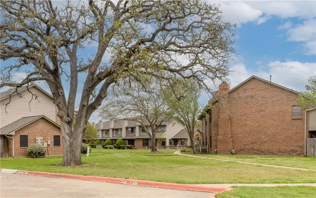 a view of a big house with a big yard and large trees