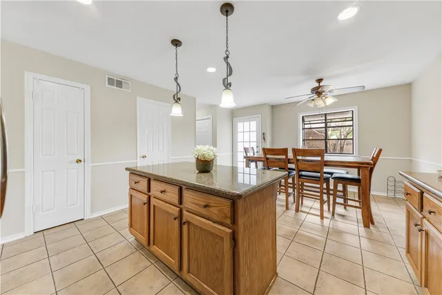 a kitchen with stainless steel appliances granite countertop a sink a stove a dining table and chairs with wooden floor