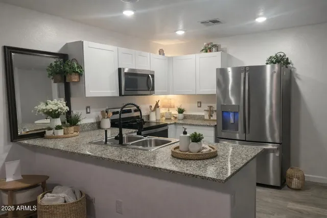 a kitchen with stainless steel appliances granite countertop a sink a stove a refrigerator and white cabinets