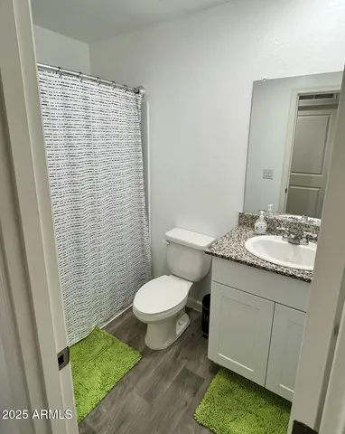 a bathroom with a granite countertop toilet sink and mirror