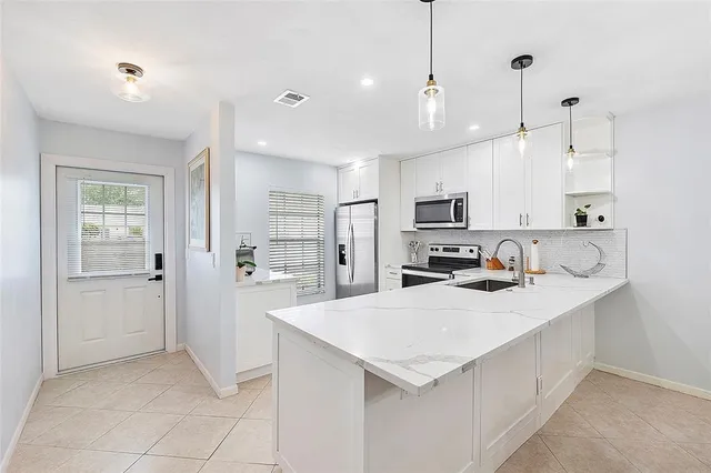 a kitchen with a sink a stove a refrigerator and white cabinets