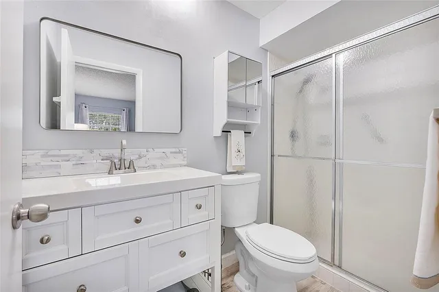 a bathroom with a toilet a sink a mirror a vanity and shower