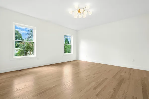 a view of empty room with wooden floor and window