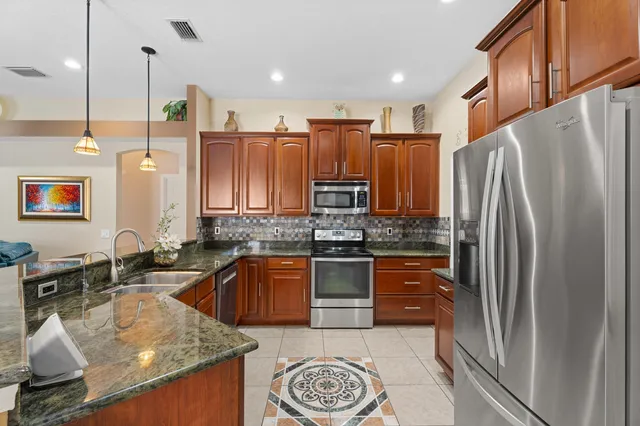 a kitchen with stainless steel appliances granite countertop a sink refrigerator and cabinets